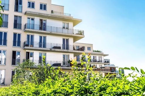 Ein modernes Haus mit Balkonen und grünen Pflanzen im Vordergrund